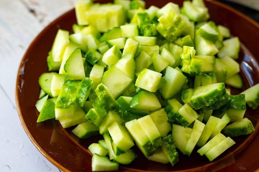 Copped cucumber on a brown plate.