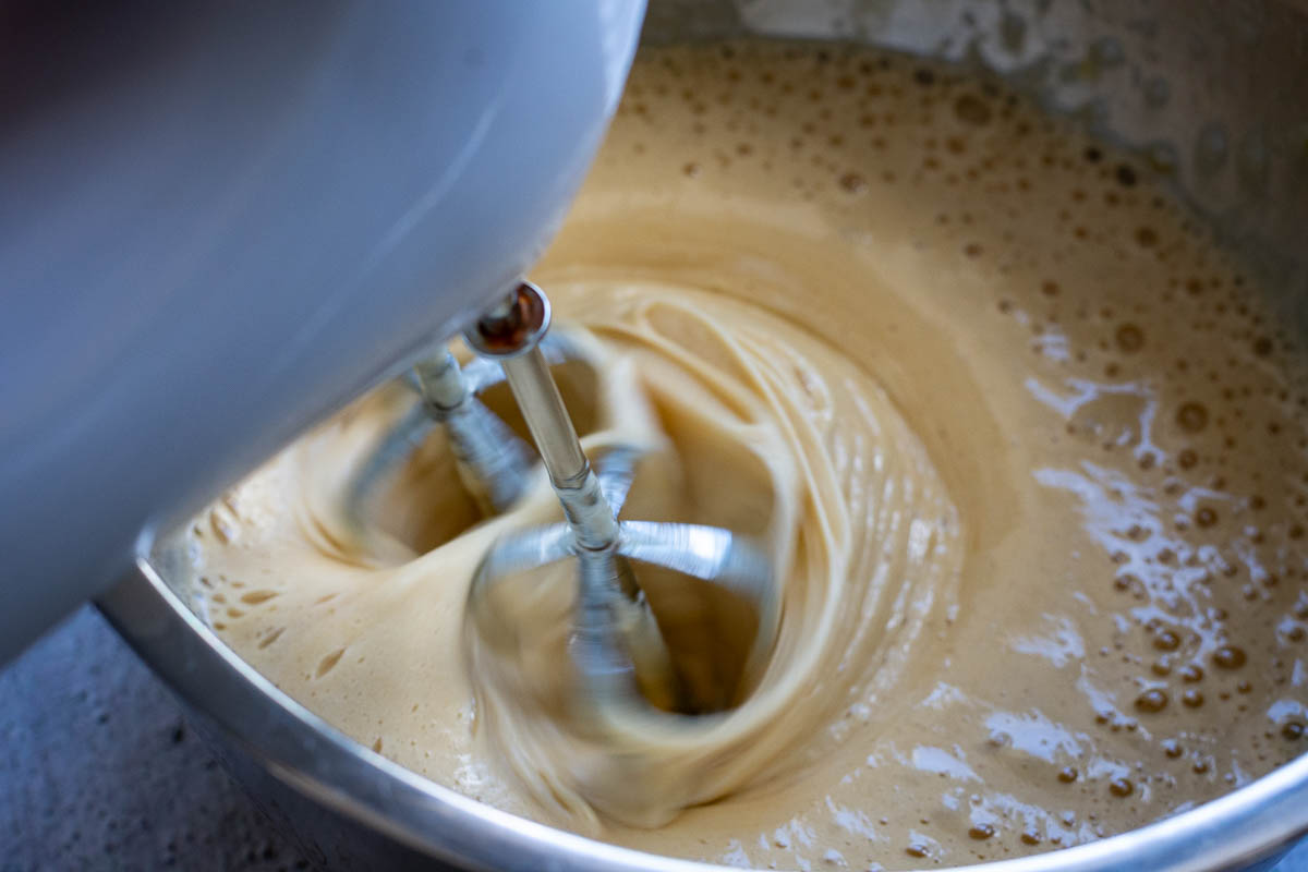 Thick and creamy cake batter beaing beaten with a mixer.