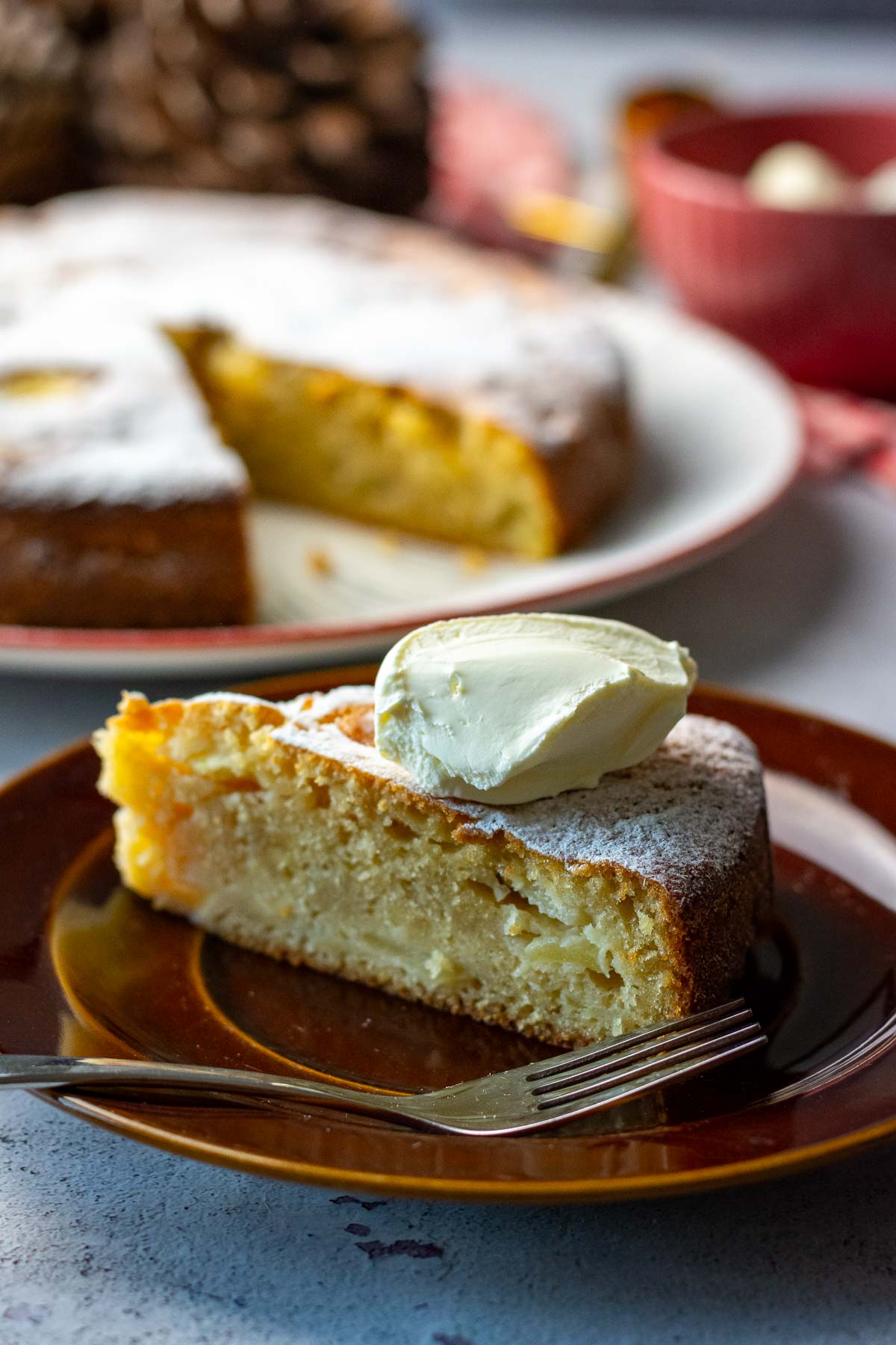 A slice of apples cake with sour cream on top.