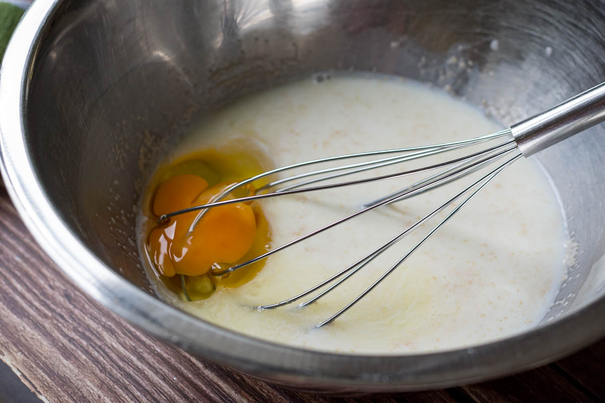 An egg added to the milk, yeast and sugar mixture. with a baloon whisk in it. 