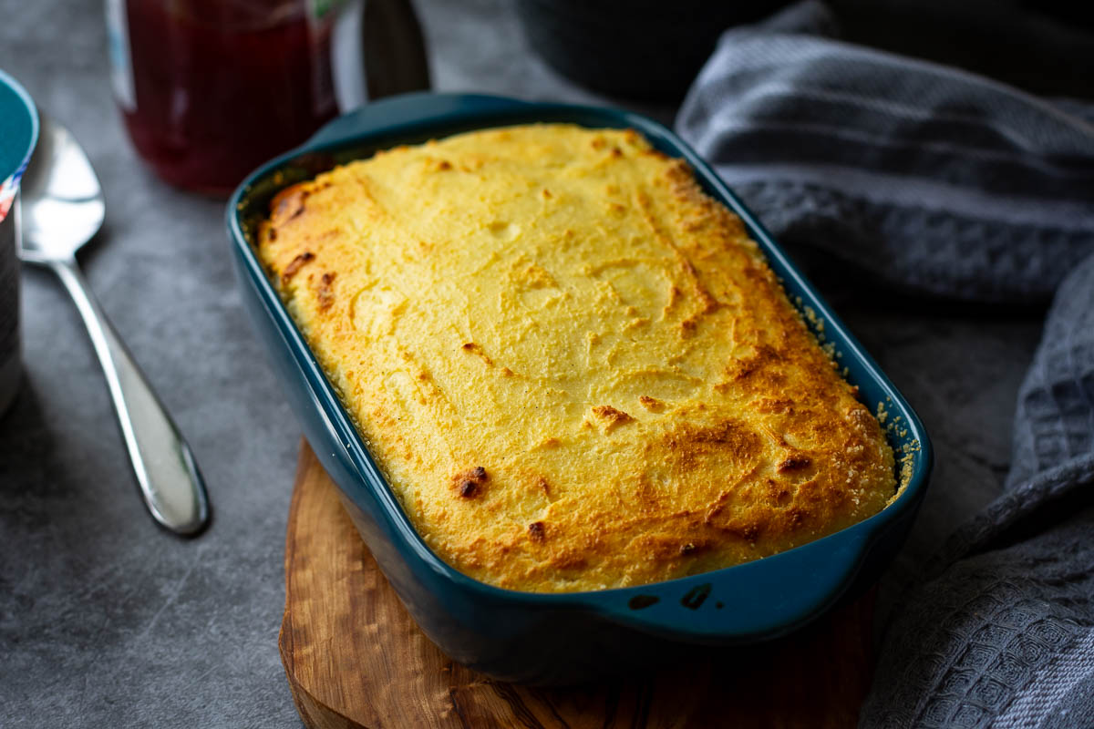 Lithuanian breakfast cheesecake in a blue baking dish on a wooden board.