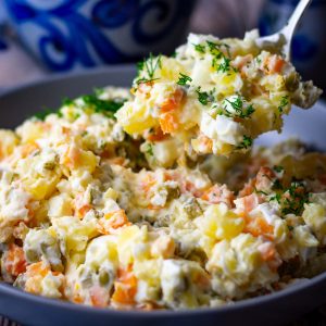 A spoonful of lithuanian boiled vegetable salad being picked up from a bowl.