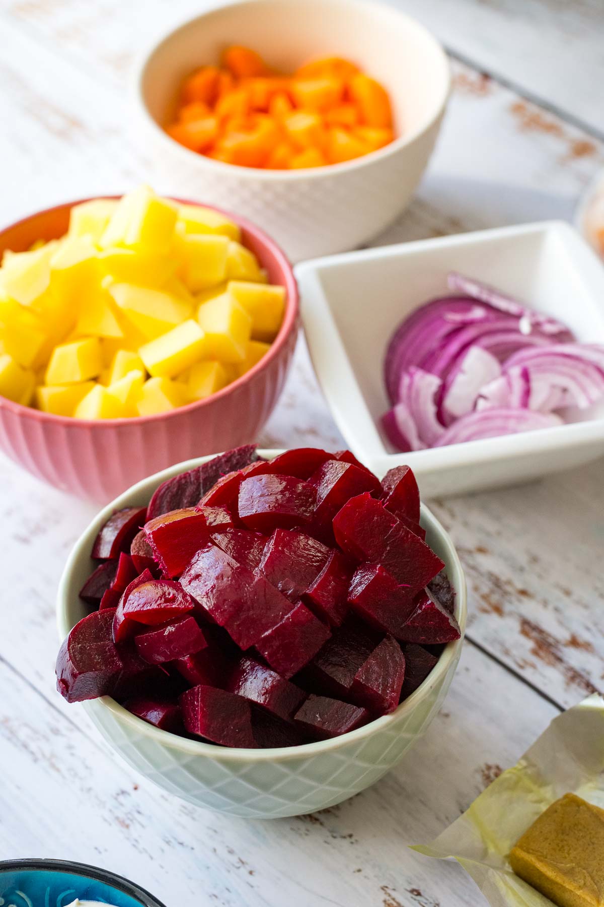 All the veggies chopped and sliced in small bowl on a wooden white table. 