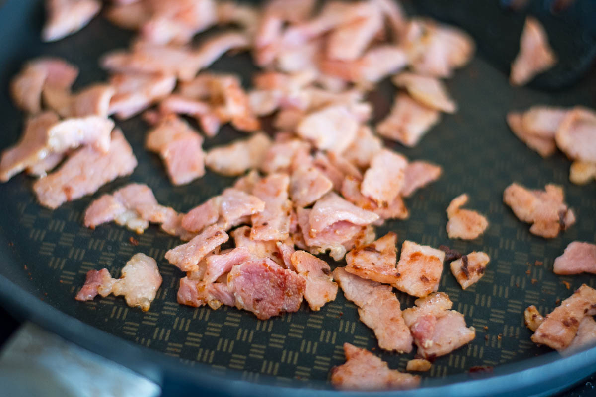 Bacon crisping up in a frying pan. 