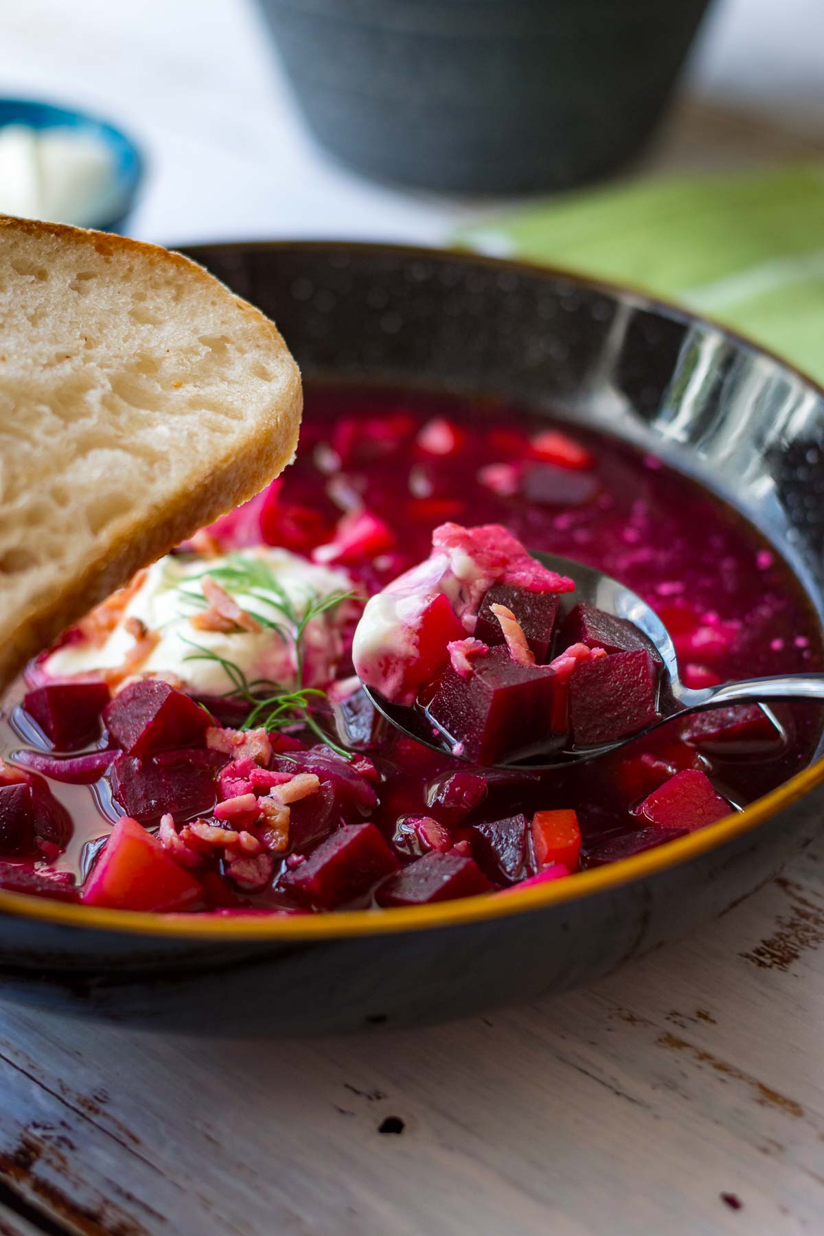 Lithuanian Beetroot Soup with a dollop of sour cream on top and a slice of bread.
