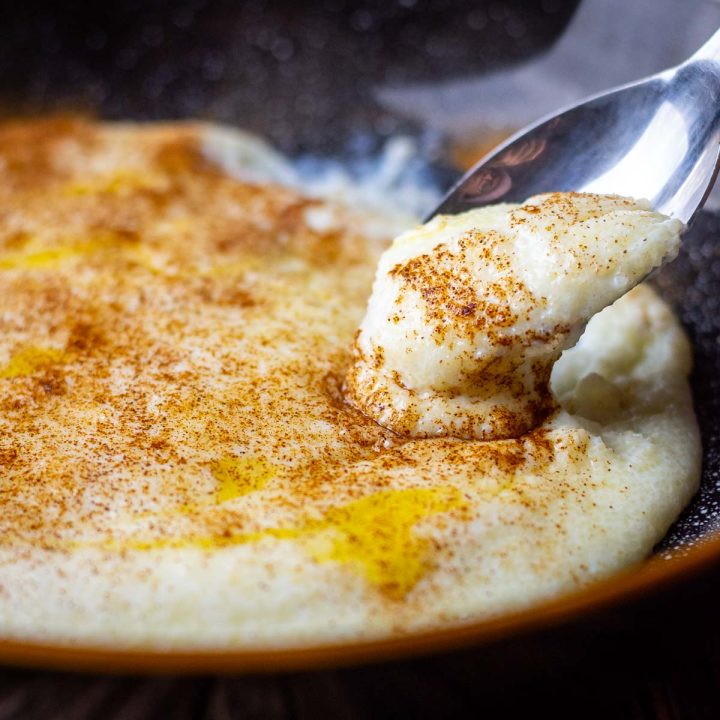 A spoonful of creamy semolina porridge being picked up from a bowl.