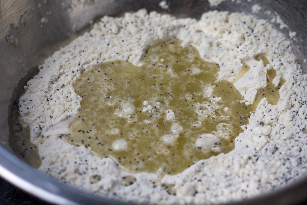 Wet ingredients boured into the dry ingredients in a metal bowl.