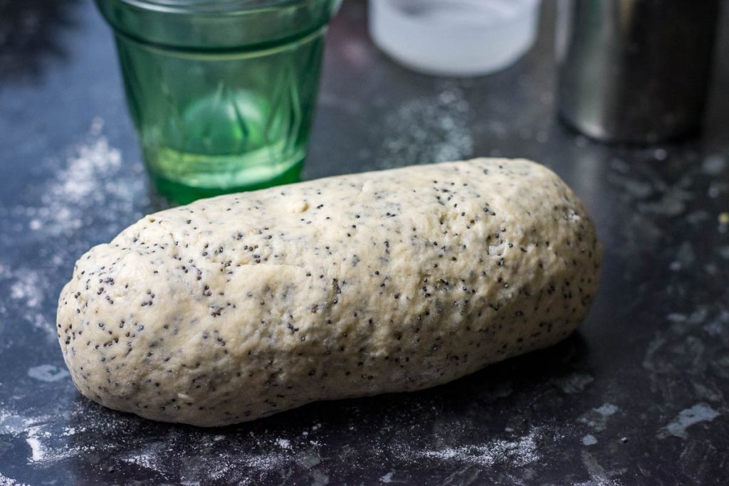 A cilinder of kuciukai dough on a dark kitchen surface.