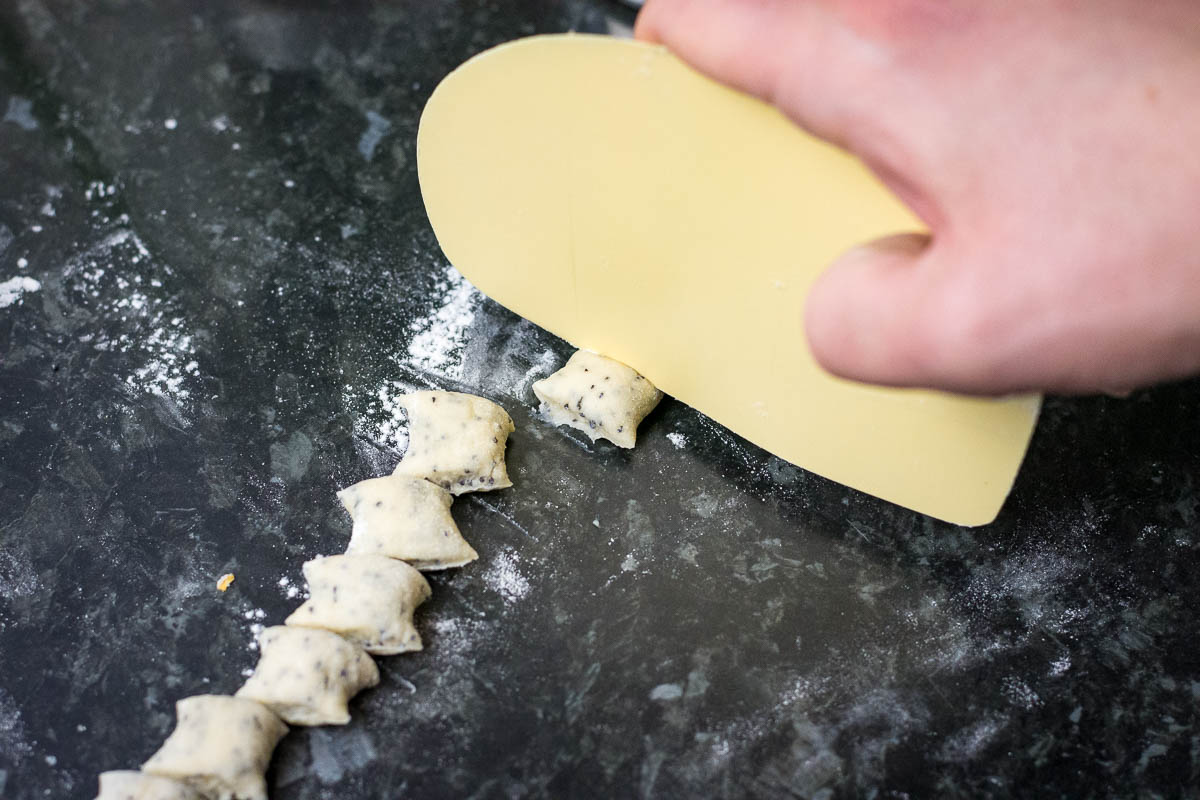 Cutting the dough strings into small biscuits.
