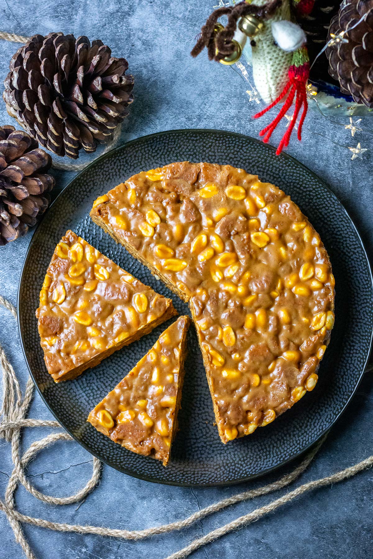 LIthunian Caramel Fridge Cake on a b;lack plate on a grey surface decorated with pine cones.