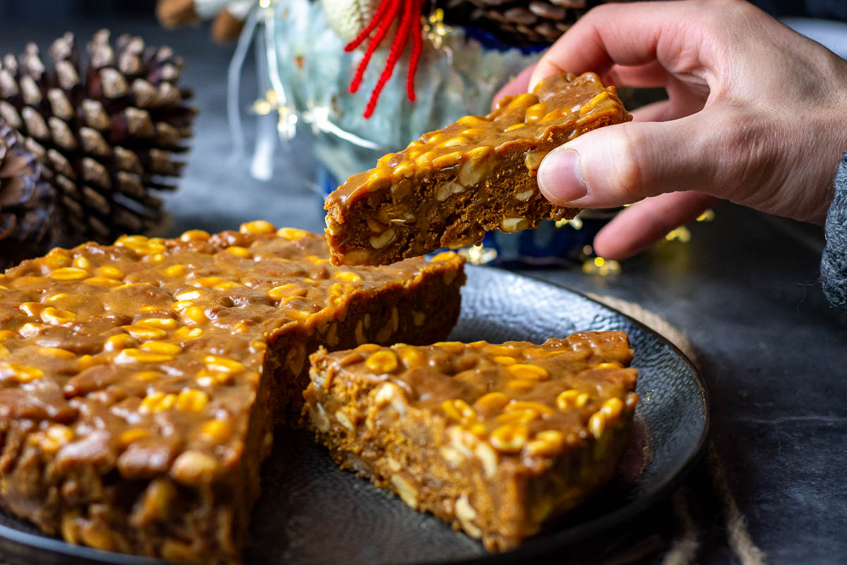 A slice of no bake caramel biscuit cake being picked up by a hand.