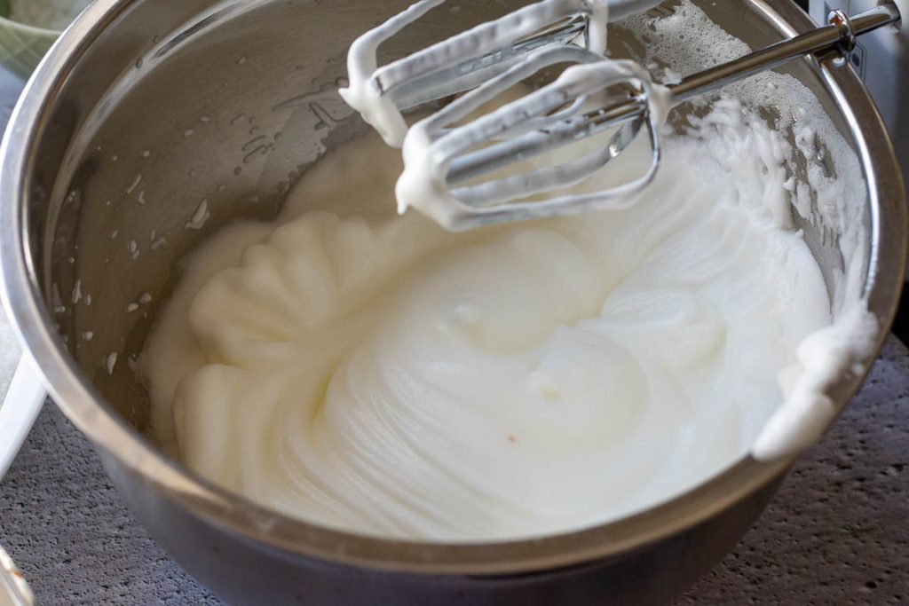 Egg whites whisked to stiff peaks in a metal bowl.