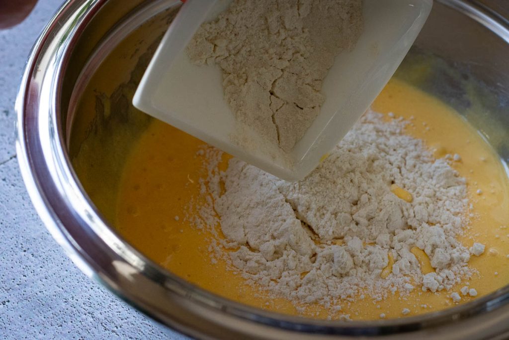 Adding flour to the egg yolk and sugar mixture.