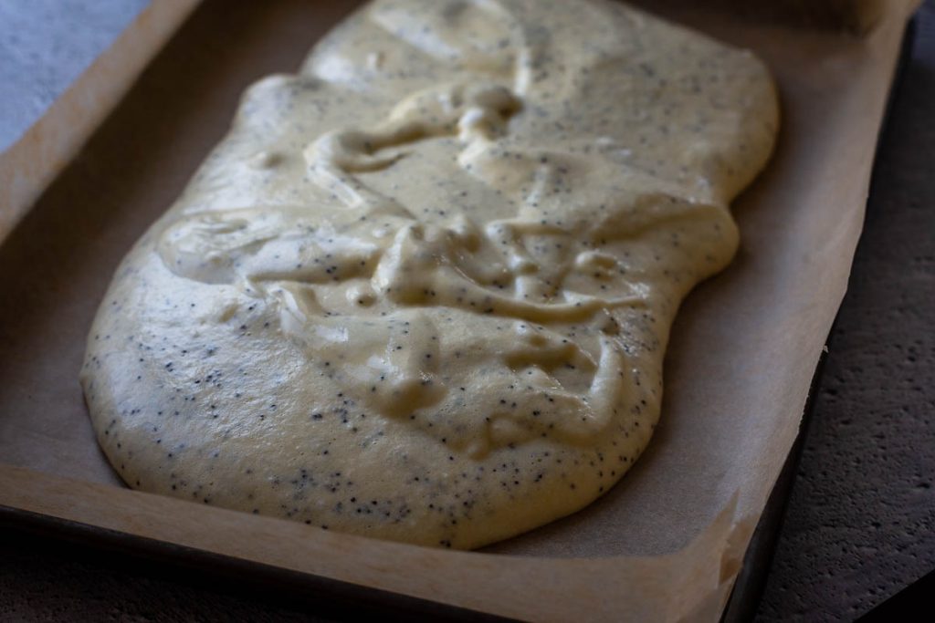 Sponge batter poured into the baking tray lined with parchment paper.