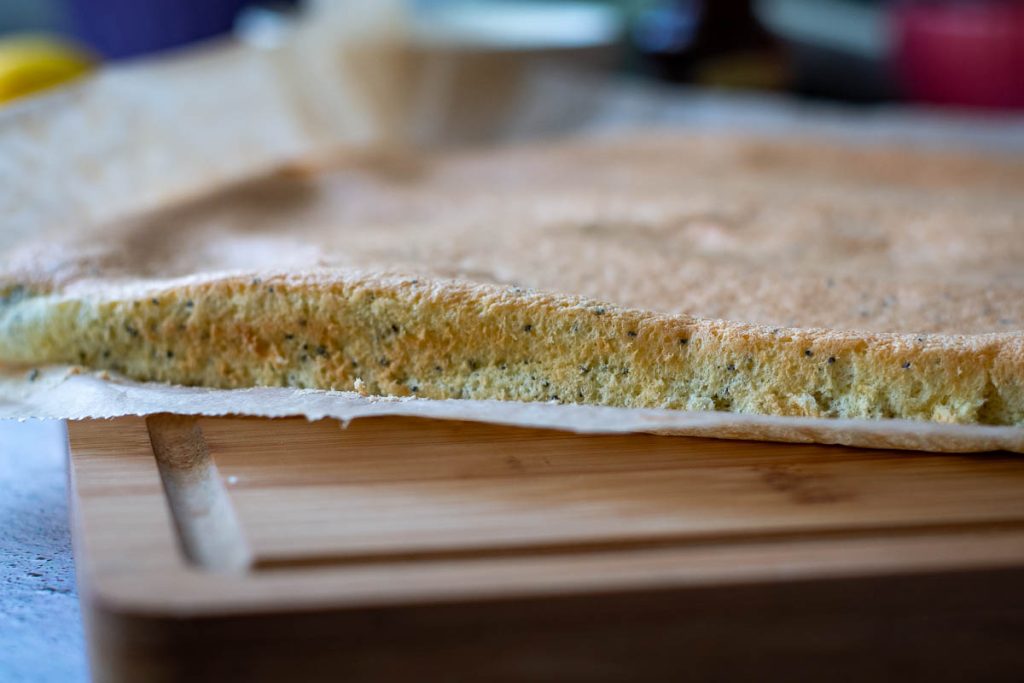 Sponge for the farmers cheese roll cake on a wooden board.