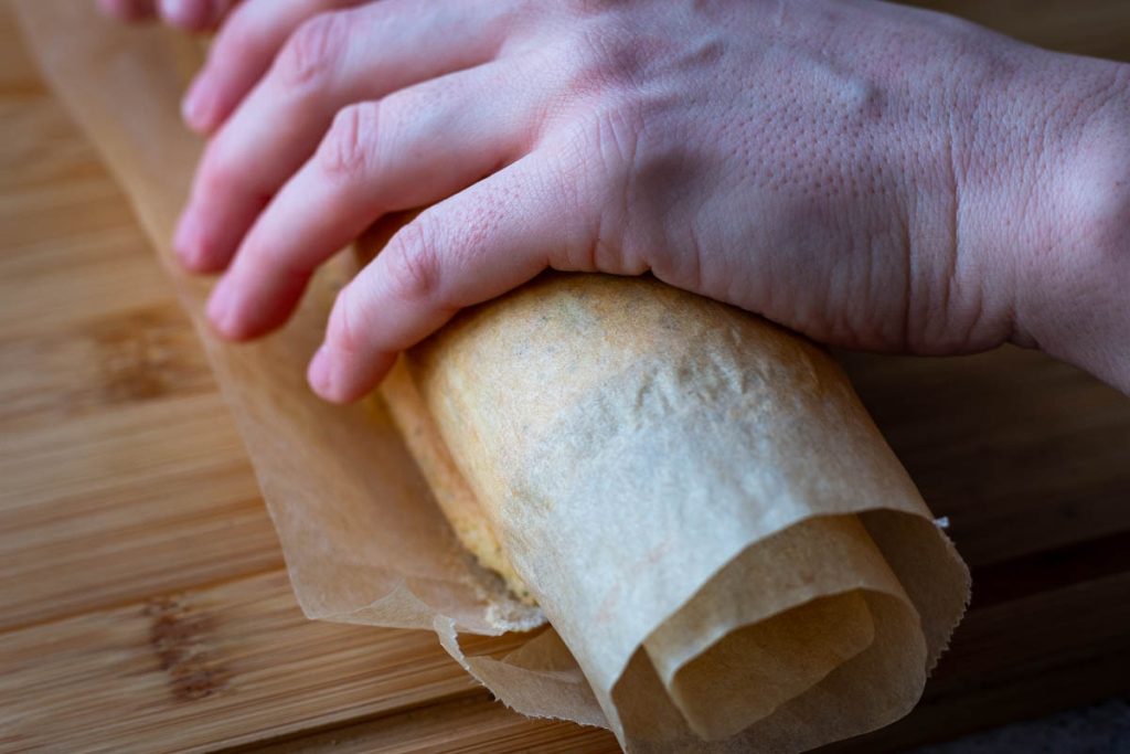 A roll of warm sponge in a parchemnt paper held by hands.