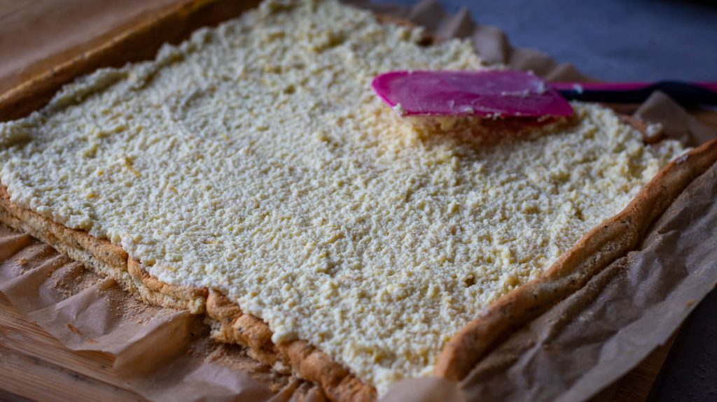 Spreading farmers cheese on the sponge with a rubber spatula.