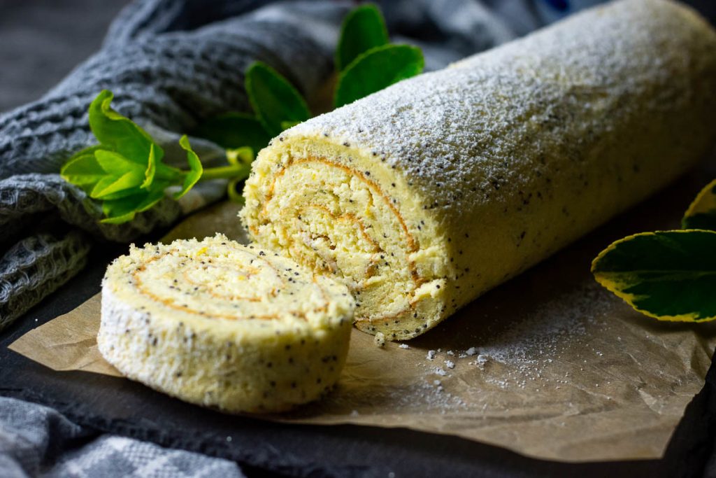 A slice of Lithuanian Farmers Cheese Roll Cake cut on a black board.