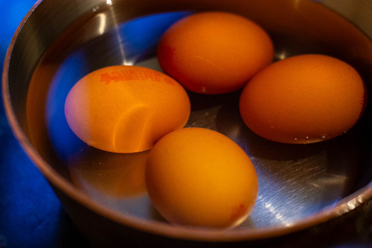 Four eggs in a copper pan.