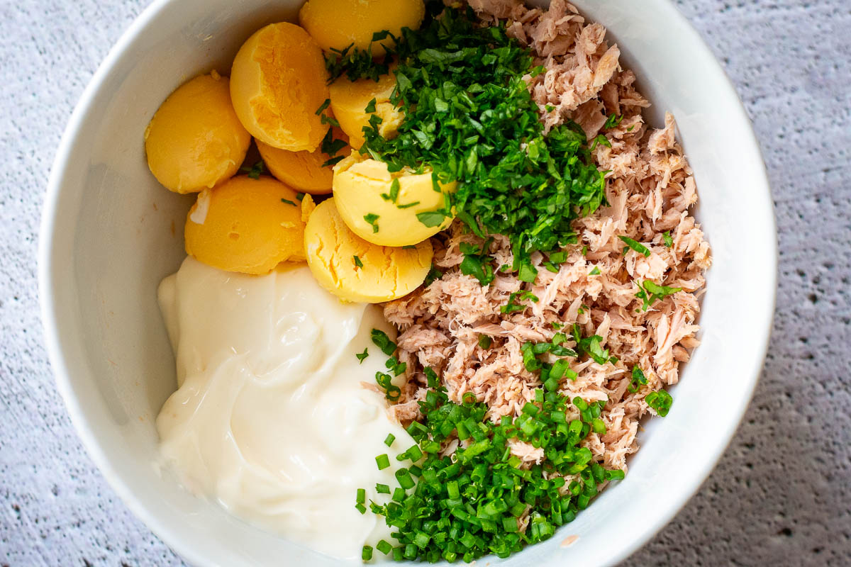All ingredients for tuna filling for eggs in a small white bowl.
