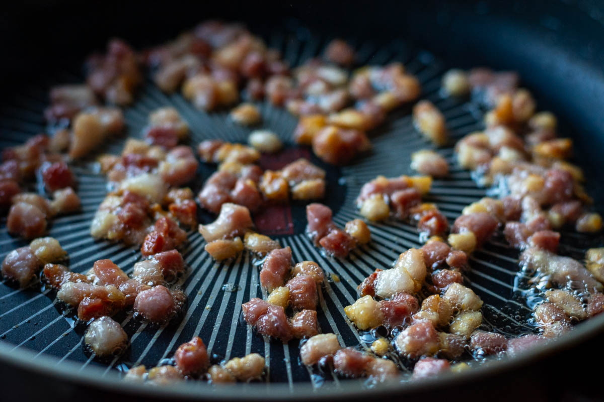 Crispy bacon cubes in a frying pan. 