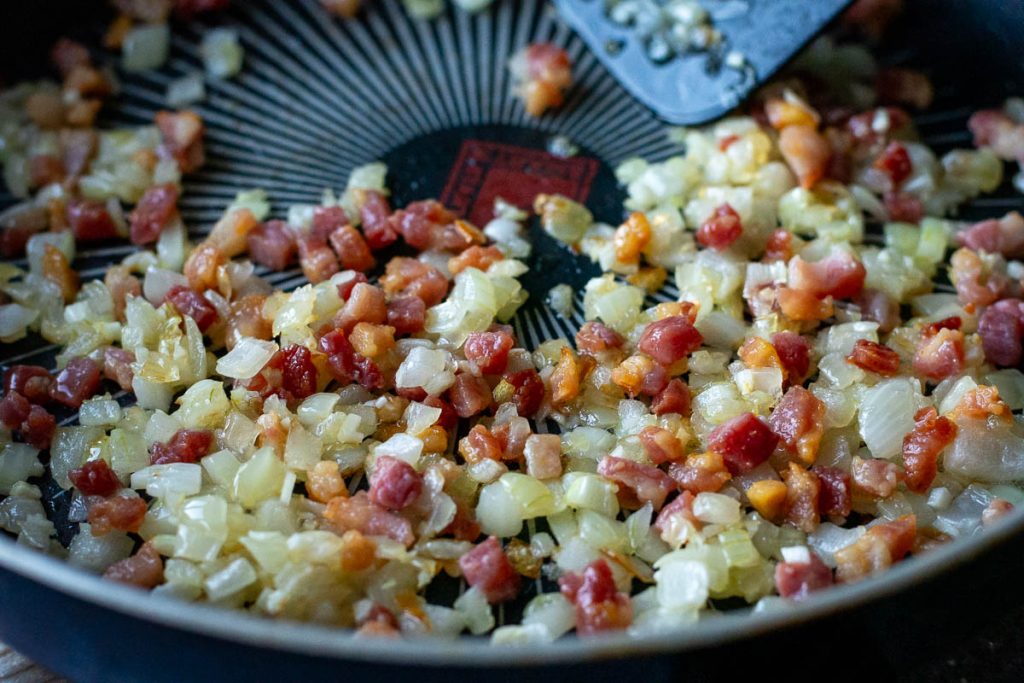 Crispy bacon added back into the pan with onions and garlic. 