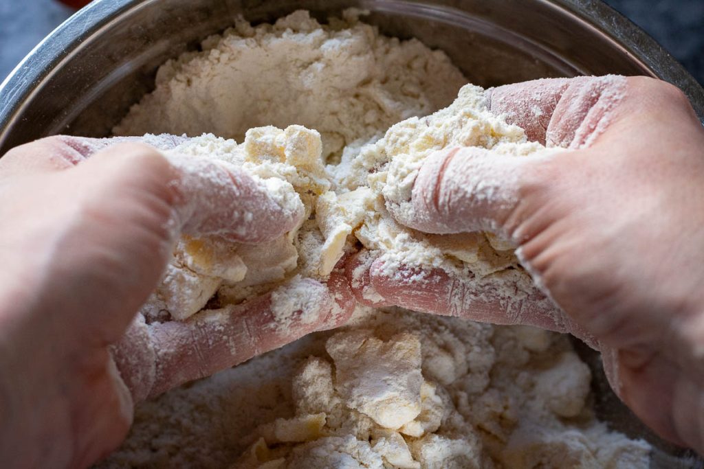 Rubbing cold butter into dry ingredients between fingertips. 