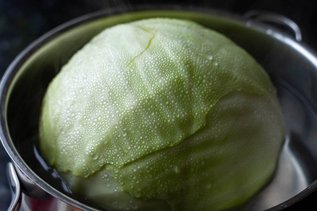 Cabbage head in hot water in a pan. 