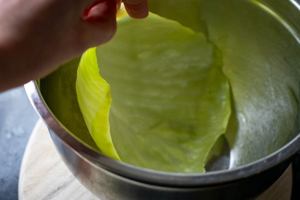 Placing a large cabbage leaf in a metal bowl. 
