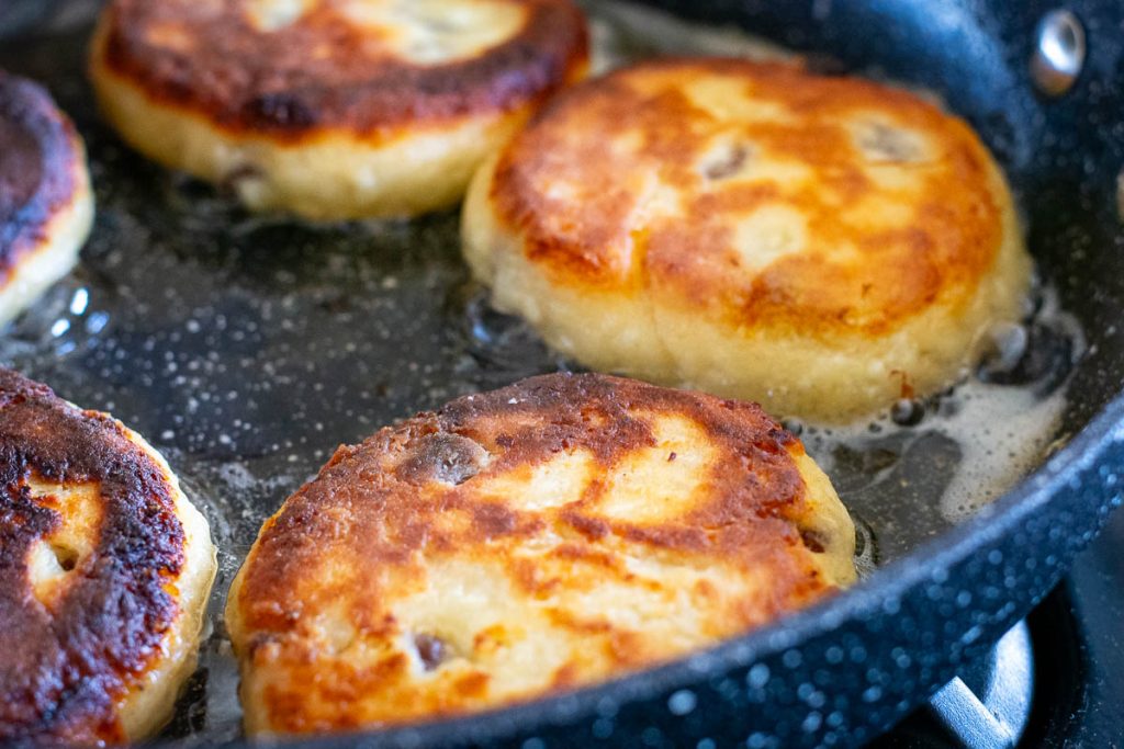 Flipped pancakes showing golden brown side in a frying pan. 