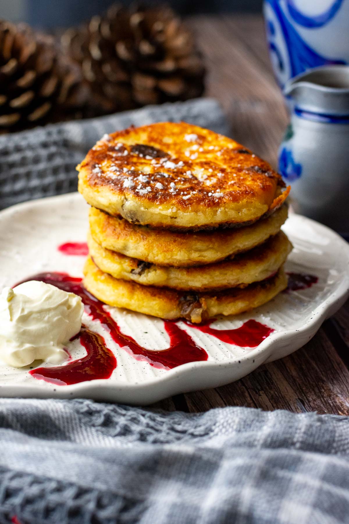 A stack of 4 farmers cheese pancakes served with berry coulis and sour cream. 