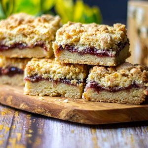 5 raspberry crumble squares arranged on a wooden board on a wooden table.