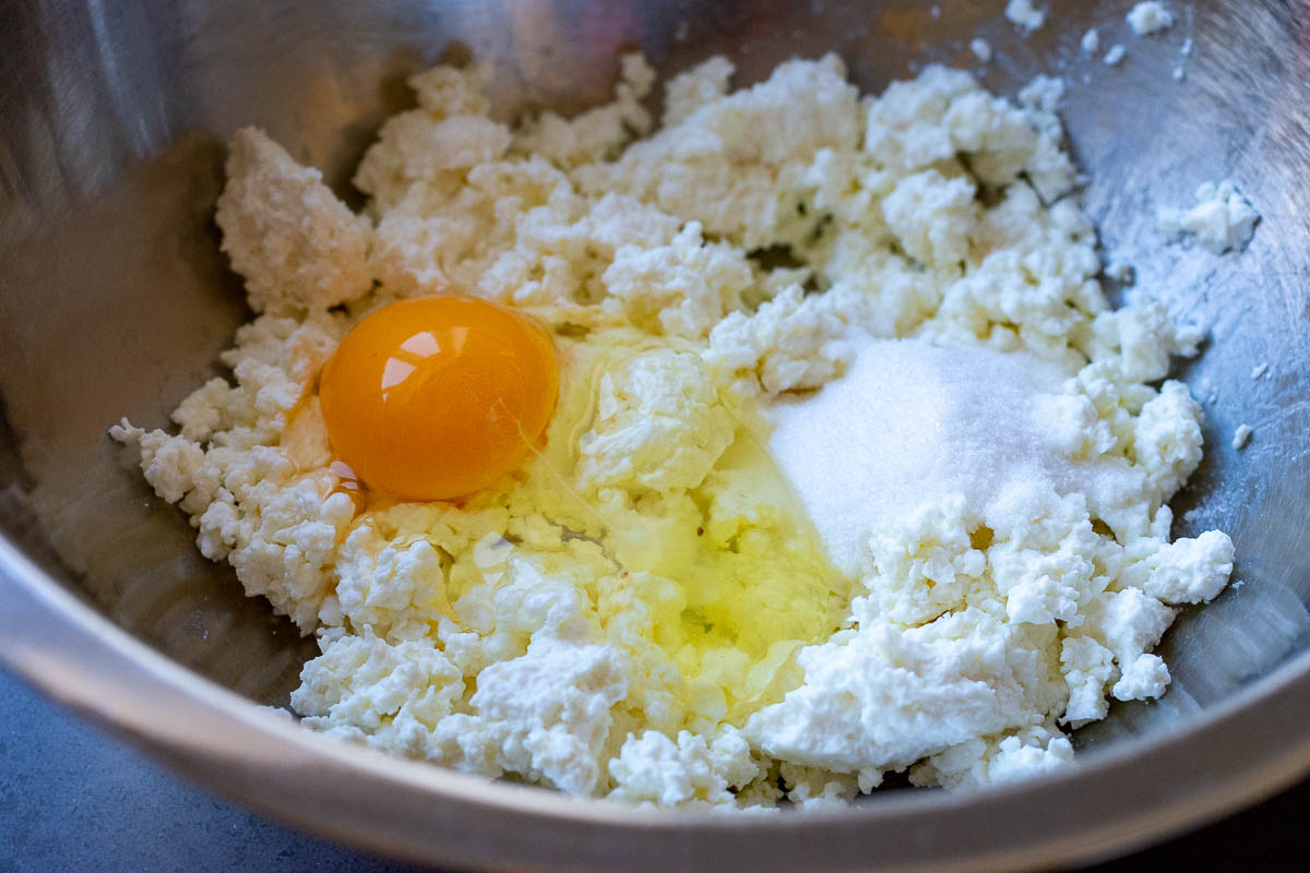 Farmers cheese, egg and sugar in a large metal mixing bowl. 