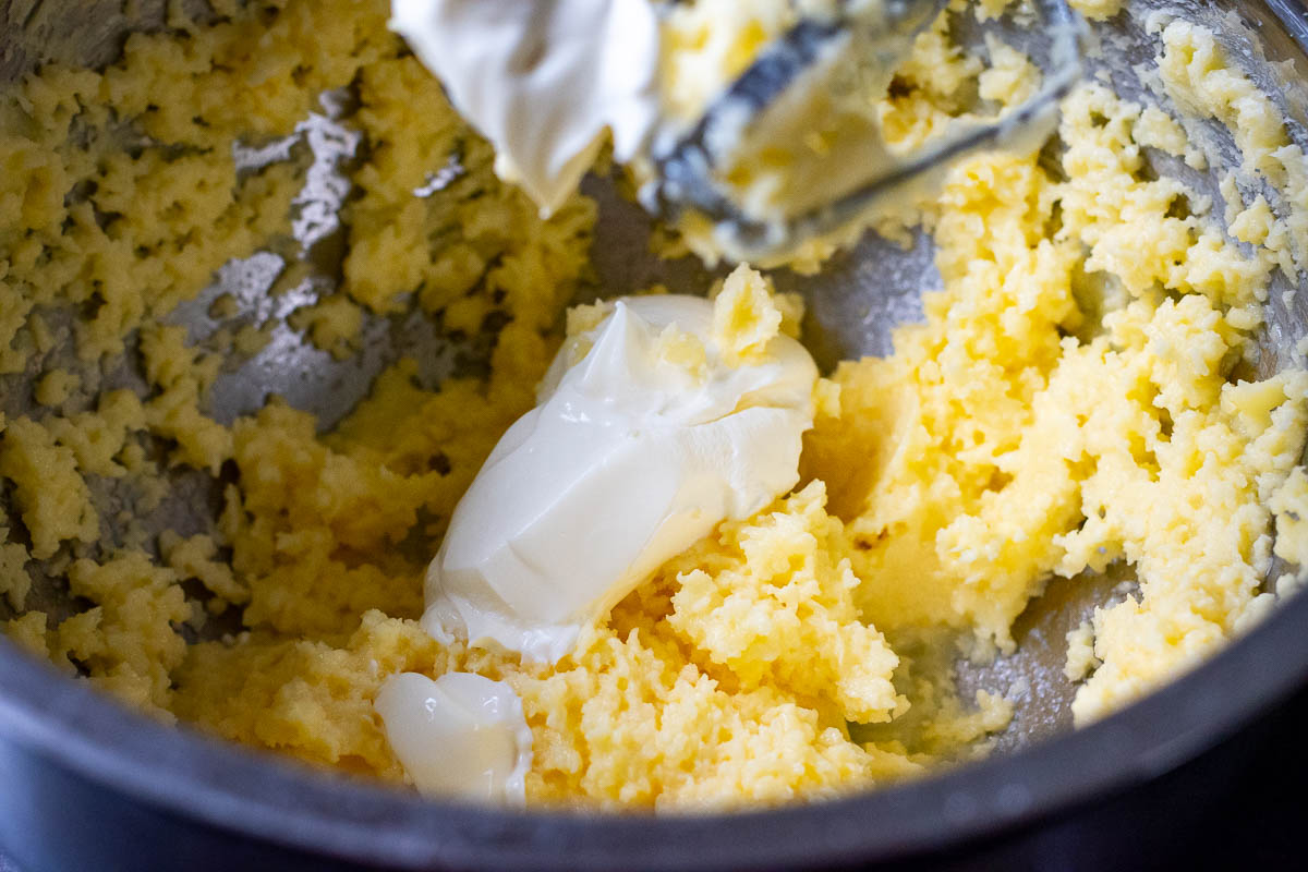 Beating butter, sugar, egg and sour cream in a large mixing bowl with a handheld electric mixer.