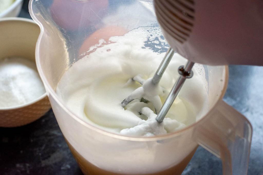 Whisking egg whites to stiff peaks in a plastic jug.