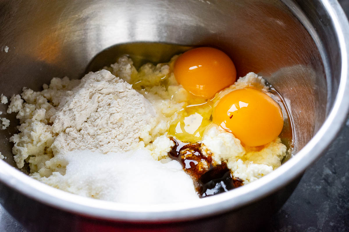 Ingredients for the farmers cheese filling in a large metal bowl.