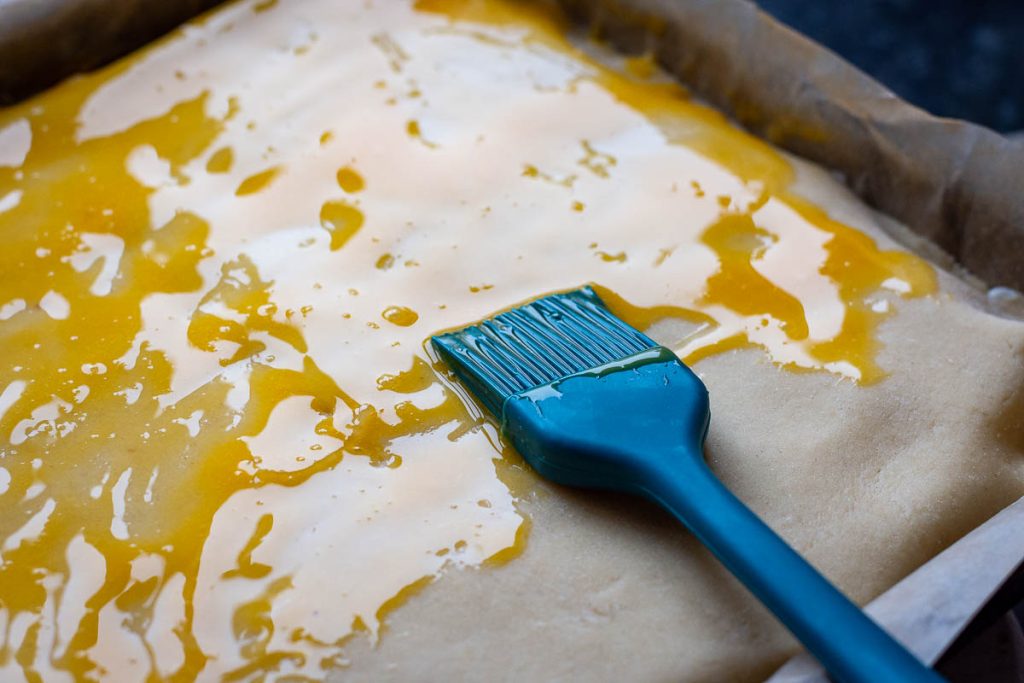 Brushing the top of the pastry with egg yolks.