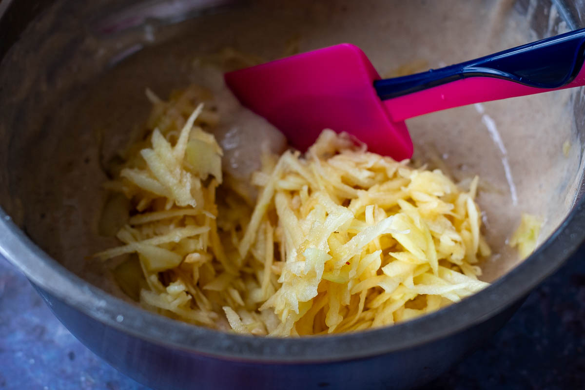 Stirring in grated apples into the pancake batter. 