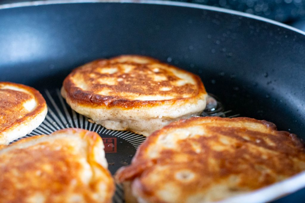 Four pancakes flipped over in a frying pan. 