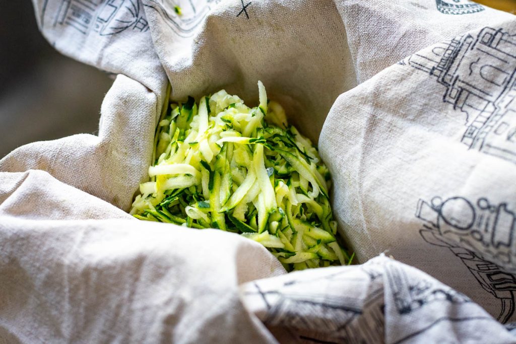 Coarsely grated zucchini in a clean linen tea towel.