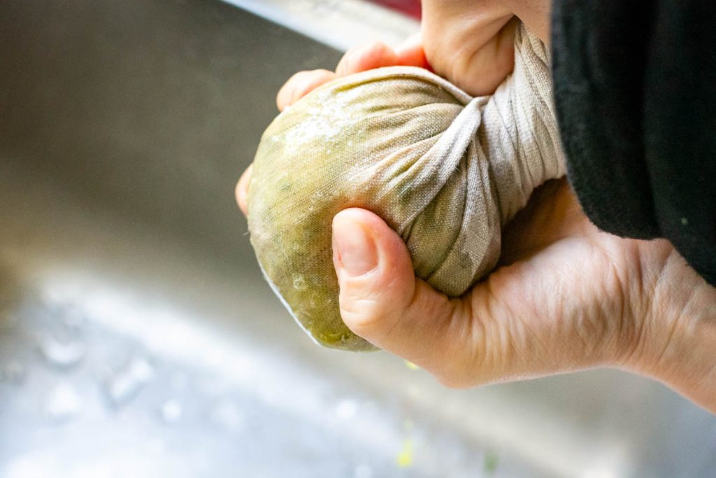 Squeezing the moisture out of the green grated zucchini.