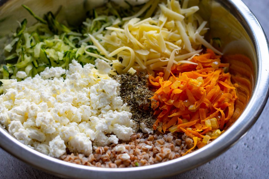 All buckwherat casserole ingredients except for eggs unmixed in a large metal bowl.