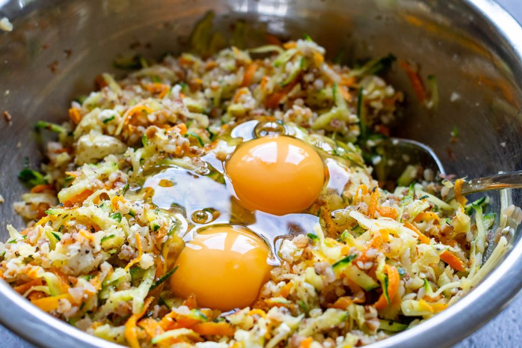 Mixed lithuanian casserole ingredients with two eggs cracked on top.