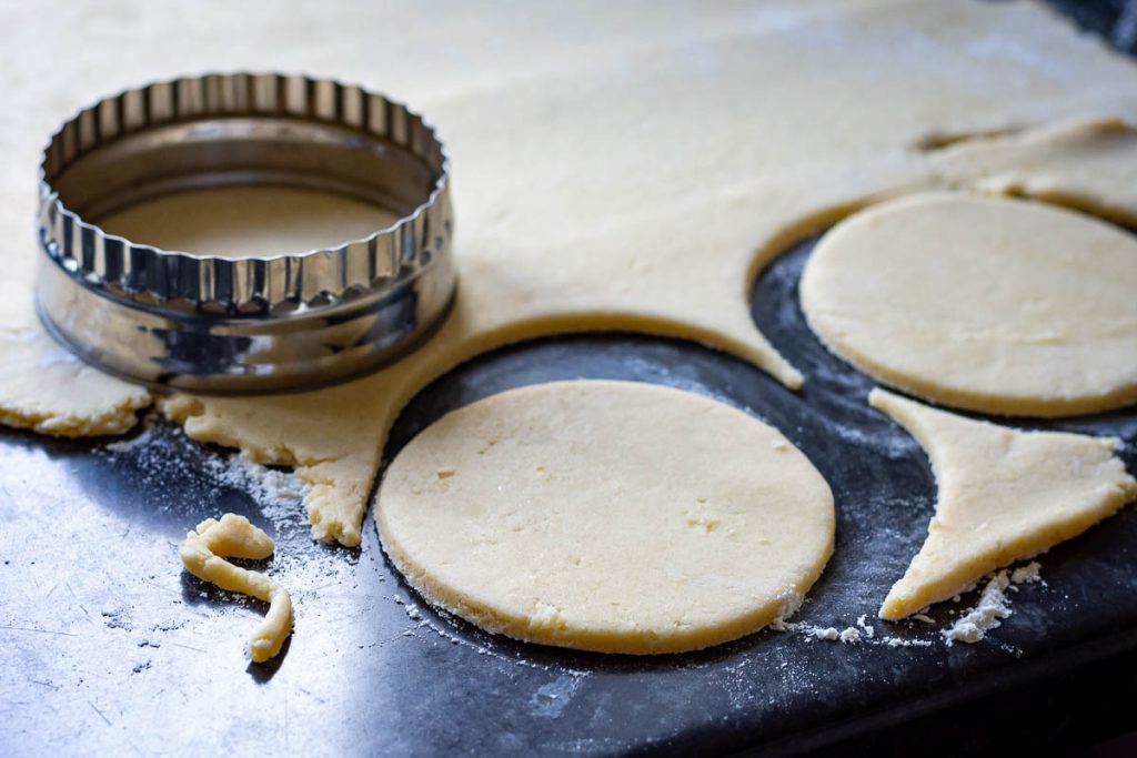 Stamping out circles of pastry with a cookie cutter.