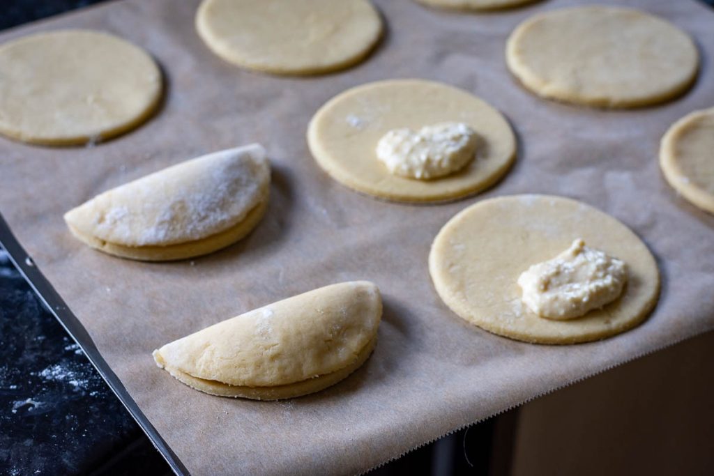 Adding spoonfuls of farmers cheese filling onto each circle of sour cream pastry.