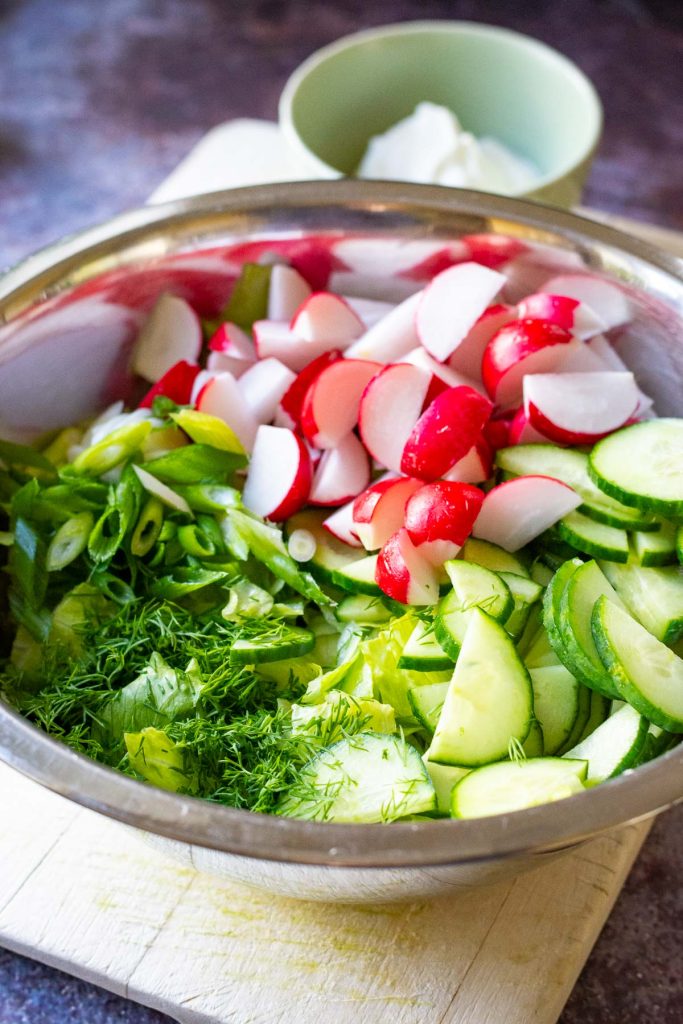 Chopped and shredded vegetables and herbs in a large mixing bowl. 