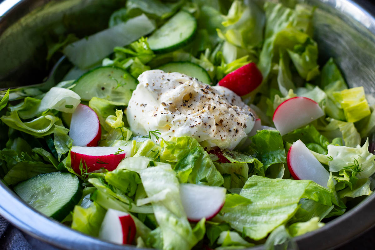 A dollop of sour cream and seasoning on top of the fresh vegetables.