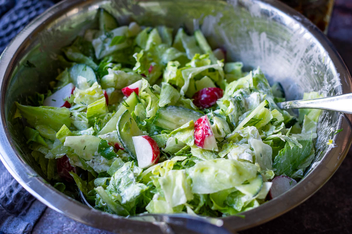 Lithuanian salad with cuucmber, radish and lettuce mixed in a large mixing bowl. 