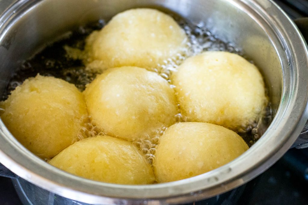 Lithuanian doughnuts frying in oil.