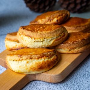 A bunch of Lithuanian sour cream pastries filled with farmers cheese on a small wooden board.